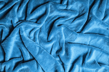 Wavy soft blue blanket background. Winkled plush canvas texture.