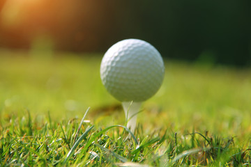 Blurred golf ball on tee in the evening golf course with sunshine in thailand