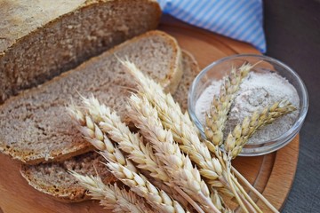 Obraz premium Healthy bread made of whole wheat flour and ears on a wooden Board.