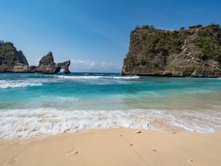Fototapeta na wymiar Big rocks in the ocean with white sand at Atuh beach on Nusa Penida island, Indonesia. November, 2018