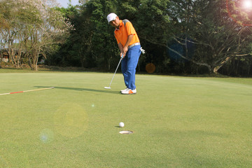 Golfer putting golf ball on the green golf