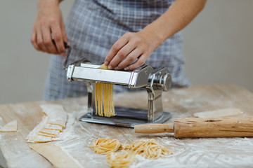 A young woman who prepares noodles with a special pasta machine at the table