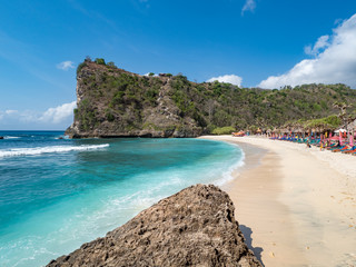 Exotic destination background with tuquoise sea water, palm trees, white sand beach and golden sun light. Warm natural colours. Top view. Atuh beach, Nusa Penida Island, Bali, Indonesia. October, 2018