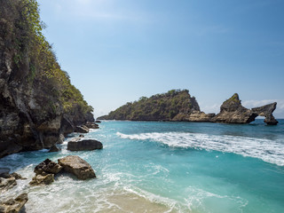 Fototapeta na wymiar Exotic destination background with tuquoise sea water, palm trees, white sand beach and golden sun light. Warm natural colours. Top view. Atuh beach, Nusa Penida Island, Bali, Indonesia. October, 2018