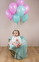 Fototapeta premium Little baby sitting in a basket with balls.