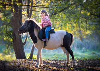 girl riding a pony in the autumn Park.