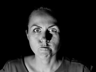 Stylish portrait of a attractive caucasian woman who seems very angry and looks directly to watcher. Black and white shot, low-key lighting. Isolated on black.