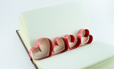 Ribbons shaped as hearts in a book for your text on white background, valentine day concept