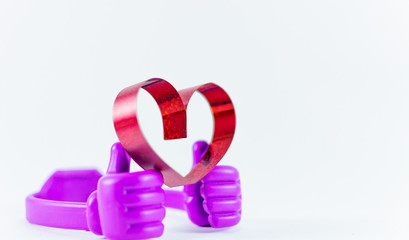 Ribbons shaped as hearts on top plastic hand on white background, valentine day concept