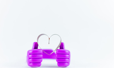 Ribbons shaped as hearts on top plastic hand on white background, valentine day concept