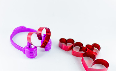 Ribbons shaped as hearts on top plastic hand on white background, valentine day concept