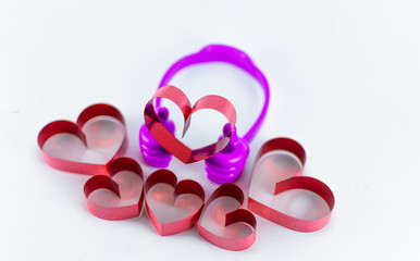 Ribbons shaped as hearts on top plastic hand on white background, valentine day concept
