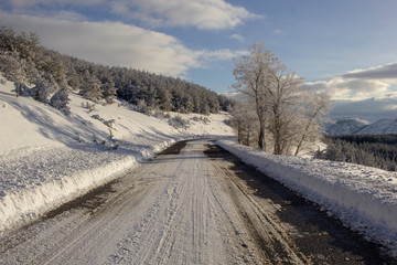 Fototapeta na wymiar snowy and icy road in mountains on snow in winter - road safety concept - winter tires obligation, dangerous road