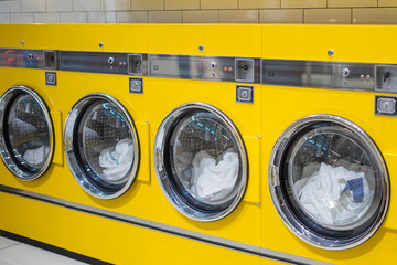 yellow coin washing machines with laundry in it