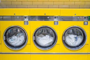 yellow coin washing machines with laundry in it