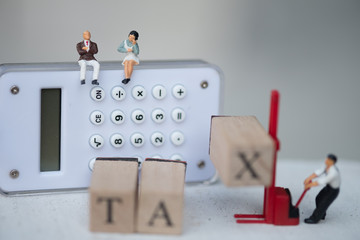 Miniature people businessman sit on calculator for think pay annual income (TAX)  year