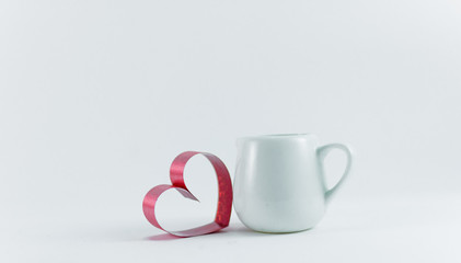 Ribbons shaped as hearts be side cup on white background, valentine day concept.