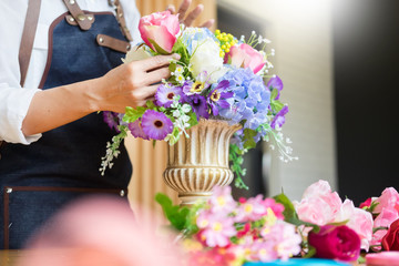 Female Florist at work using Arranging making beautiful Artificial bouquet vest at flower shop, business, sale and floristry craft and hand made concept