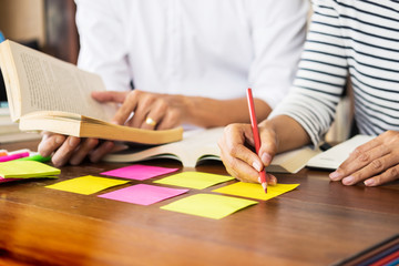Young students classmates help friend catching up workbook and learning tutoring in a library, education and school concept
