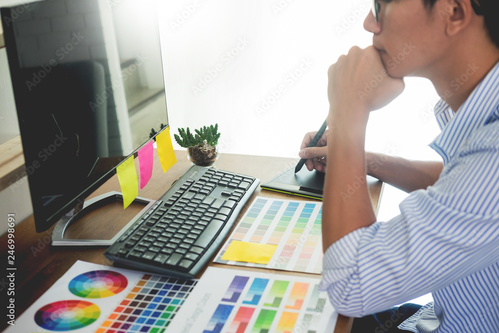 Aufkleber designer editor at work drawing sketches a new project on graphic tablet and color palette sitting a