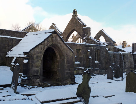 the historic ruined medieval church in heptonstall in west yorkshire cover in snow in winter with a blue sky