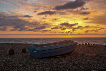 Old fishing boat on the beach, at sunrise
