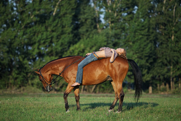 Beautiful cowgirl bareback ride her horse in woods glade at sunset 