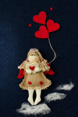 Valentine with an angel that goes on the white fluffy clouds and bears hearts on a dark background