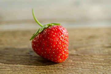 one strawberry on a wooden table