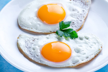 Homemade, fried chicken eggs with fresh parsley close up for a breakfast. Protein food.