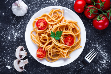 Homemade, delicious spaghetti with parsley, fresh vegetables and tomato sauce on a plate. Italian...