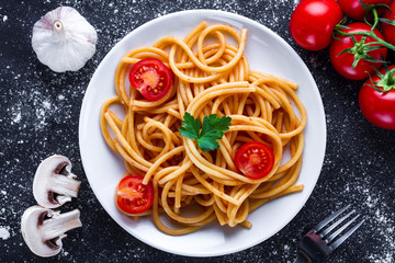 Homemade, delicious spaghetti with parsley, fresh vegetables and tomato sauce on a plate. Italian food and pasta. Top view
