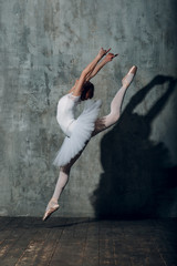 Fototapeta na wymiar Ballerina jumping. Young beautiful woman ballet dancer, dressed in professional outfit, pointe shoes and white tutu.