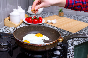 Fried homemade, chicken eggs in the frying pan sprinkling with spices for a healthy, protein breakfast