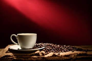 Cup of coffee and coffee beans on reddish brown background