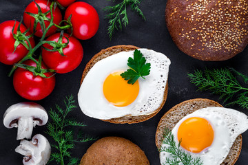 Fried chicken eggs with dill, parsley, tomatoes and sesame buns for a healthy breakfast. Top view. Protein food. Eggs sandwiches
