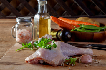 Raw chicken legs with spices and vegetables on a wooden board