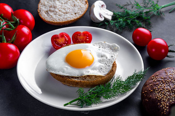 Homemade, fried egg on a plate with dill, parsley, tomatoes cherry and sesame bun for a healthy breakfast. Protein food. Eggs sandwiches.
