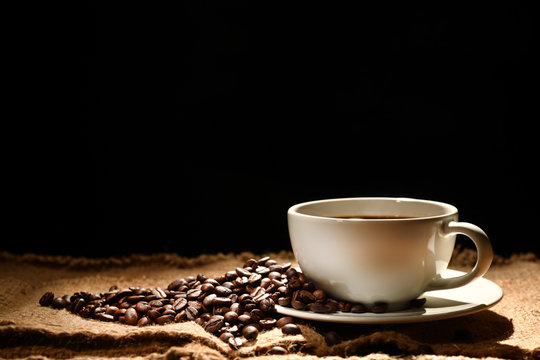 Cup of coffee and coffee beans on black background © amenic181