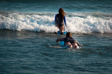 Girls in Bali on a surf board hitting the wave 