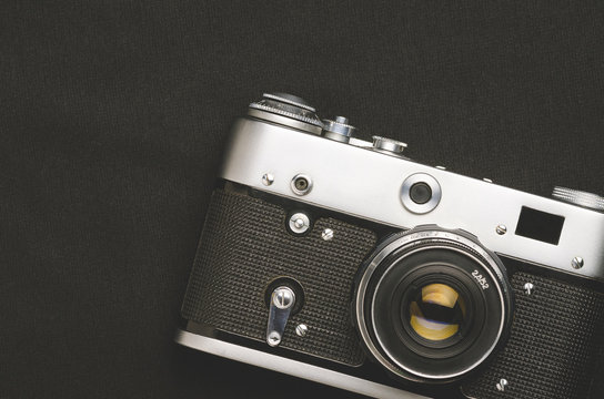 Old vintage film camera on black background, close - up, high contrast