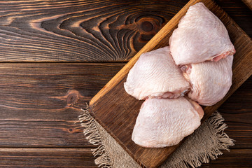 Raw chicken thigh on dark wooden background. © Natallia