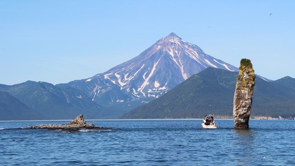 Rocky reef in the waters of the Pacific Ocean off the coast of Kamchatka, Russia. Vilyuchinsky volcano (also called Vilyuchik) is visible in the background.
