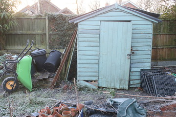 Winter landscape of wooden decaying old shed in allotment garden with raised beds, wheelbarrow,...