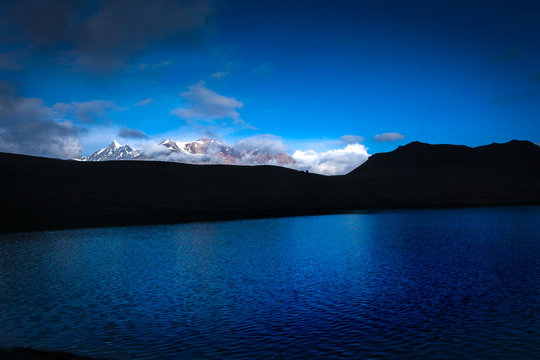 Snow capped mountains reflecting in the Chandrataal Lake at sunrise 