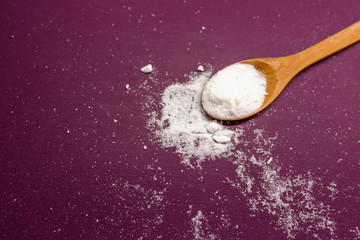 Fototapeta na wymiar White sugar in wood spoon. background of sugar cubes and sugar in spoon. White sugar on violet background.