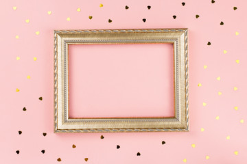 Golden photo frame with space for text, golden confetti on pastel pink background. Valentine's day background