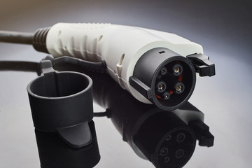 Electric car charging plug on a dark background. Eco-friendly alternative energy concept.