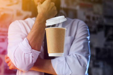 Meditative barista in a white shirt and tie and levitating paper cup of hot coffee. Background for advertising. Logo placement concept