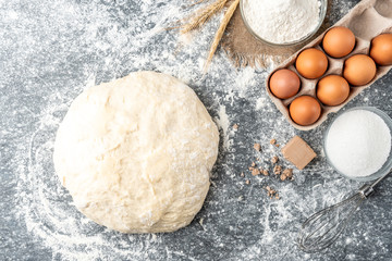Yeast dough on gray background. Baking ingredients of pressed yeast, eggs, sugar, milk and flour.  
